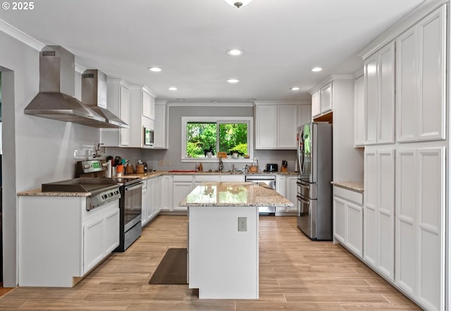 5944 SW Wilbard St, Portland, OR 97219 - kitchen featuring appliances with stainless steel finishes, wall chimney exhaust hood, white cabinets, a center island, and recessed lighting