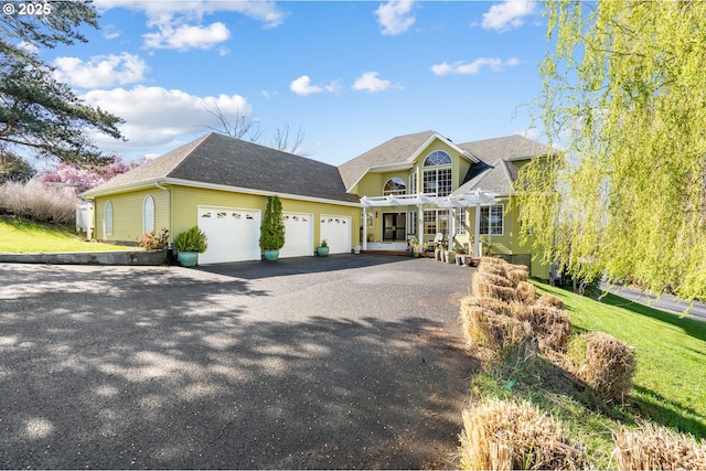 view of front of property with an attached garage, a shingled roof, and aphalt driveway