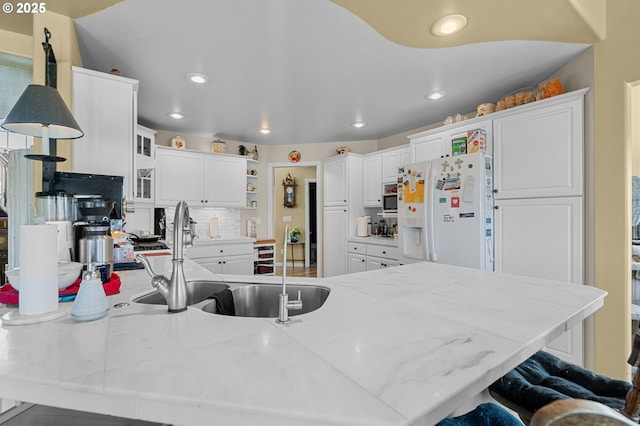 kitchen with open shelves, a sink, a breakfast bar, a peninsula, and white refrigerator with ice dispenser