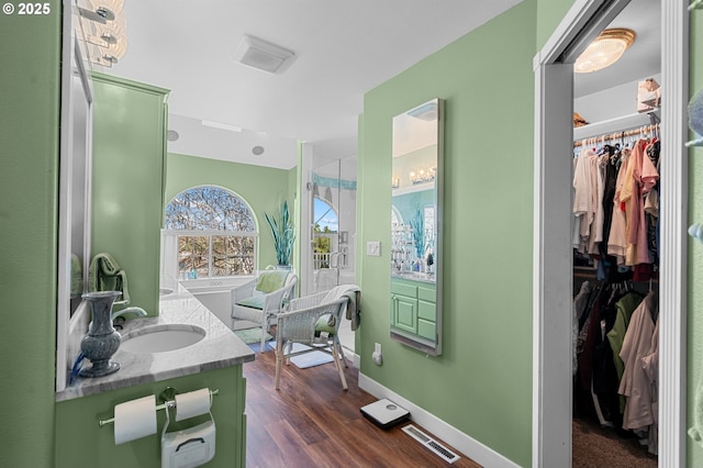 full bathroom featuring vanity, a spacious closet, visible vents, wood finished floors, and baseboards