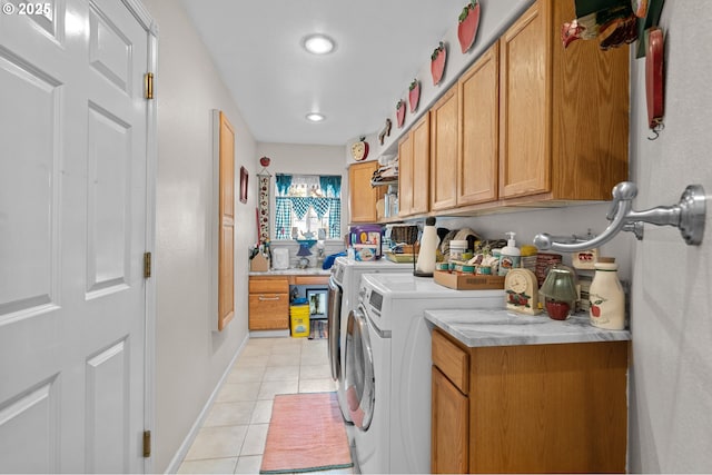 laundry area featuring washer and dryer, baseboards, cabinet space, and light tile patterned flooring