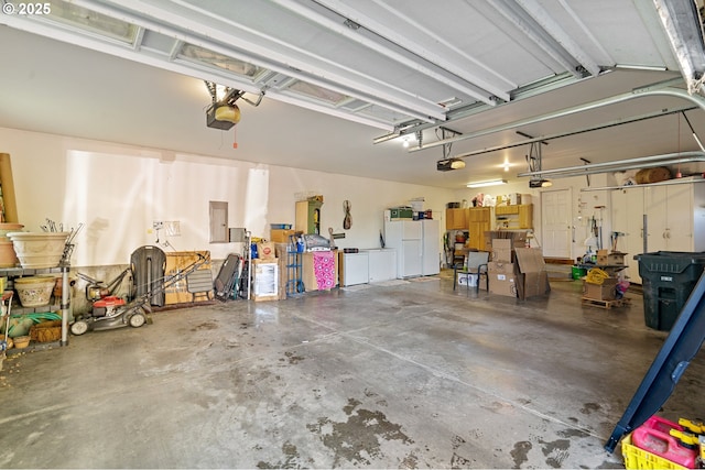 garage with freestanding refrigerator, a garage door opener, and electric panel