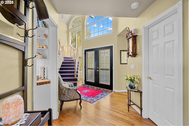 entryway featuring french doors, baseboards, stairway, and wood finished floors