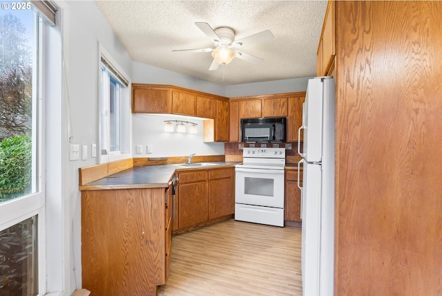 kitchen with ceiling fan, sink, white appliances, and a textured ceiling