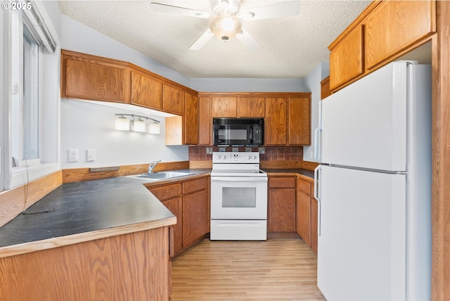 kitchen featuring ceiling fan, sink, white appliances, and a textured ceiling