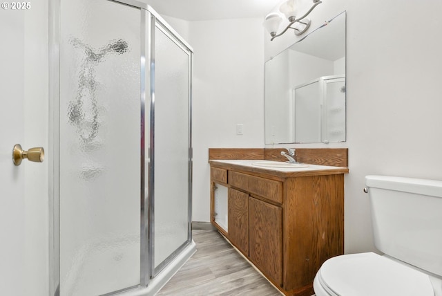 bathroom featuring toilet, vanity, a shower with door, and hardwood / wood-style floors