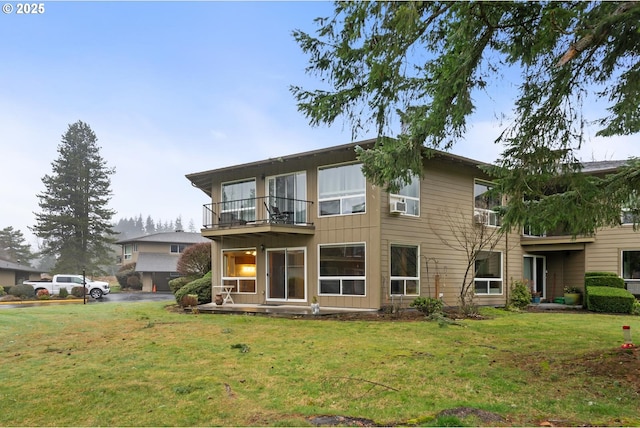 rear view of house with a yard and a balcony