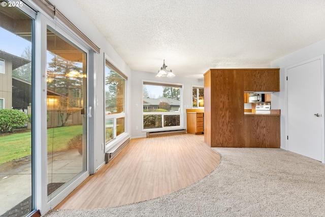 interior space with light colored carpet, a baseboard heating unit, a chandelier, and a textured ceiling