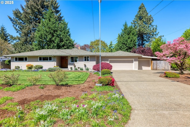 ranch-style home featuring a garage, concrete driveway, a front yard, and fence