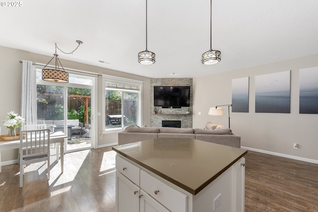 4952 SW Wentworth Ter, Beaverton, OR 97078 - kitchen featuring baseboards, a fireplace, dark wood-style flooring, hanging light fixtures, and white cabinetry