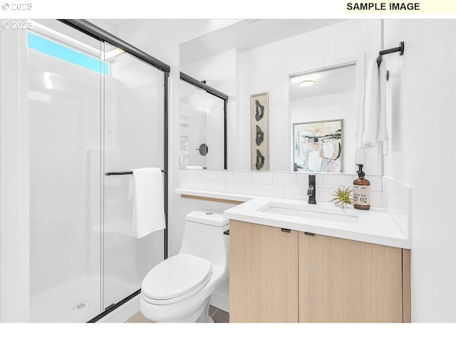 bathroom with tasteful backsplash, toilet, vanity, and walk in shower