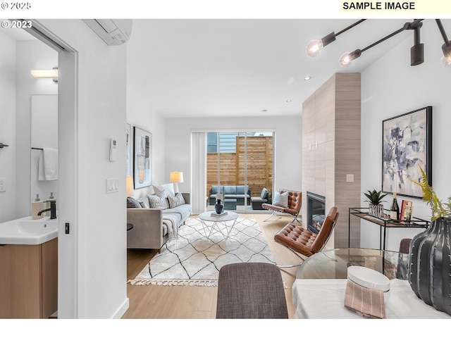 living room featuring a wall mounted AC, a fireplace, light hardwood / wood-style floors, and sink