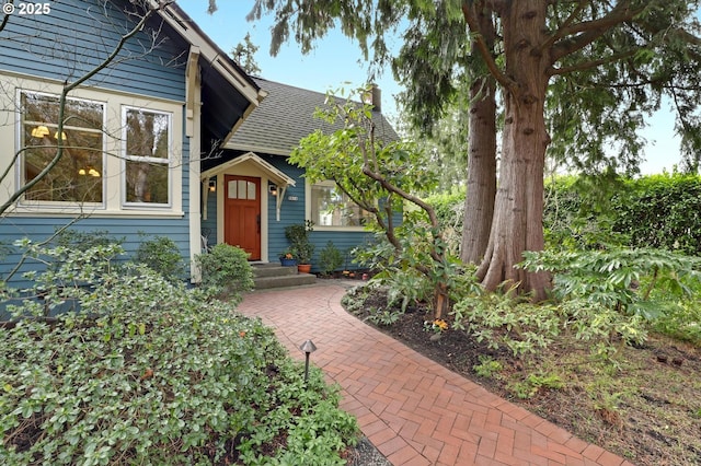 entrance to property with roof with shingles and a chimney