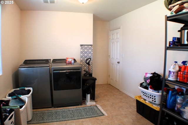 clothes washing area featuring washing machine and clothes dryer, visible vents, and laundry area