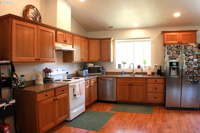 kitchen featuring dark countertops, appliances with stainless steel finishes, under cabinet range hood, and a sink