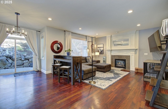 living room featuring a large fireplace, a chandelier, and dark hardwood / wood-style flooring