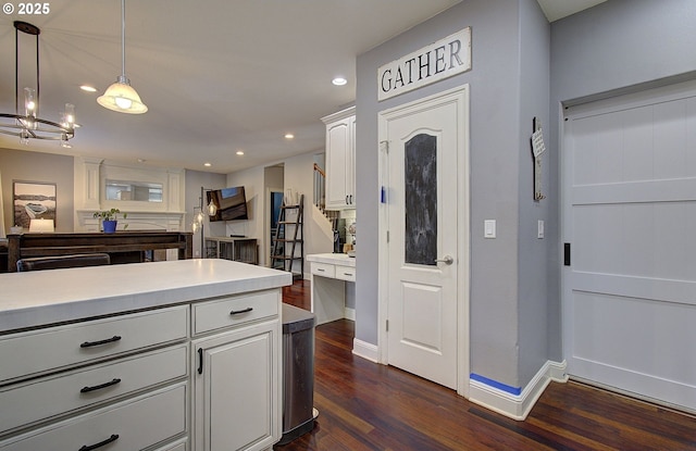 kitchen featuring white cabinets, dark wood-style flooring, baseboards, decorative light fixtures, and light countertops
