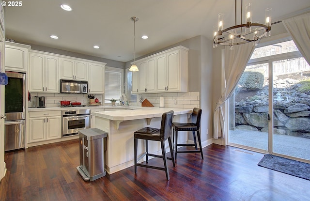 kitchen with backsplash, a notable chandelier, stainless steel appliances, and dark wood-style floors