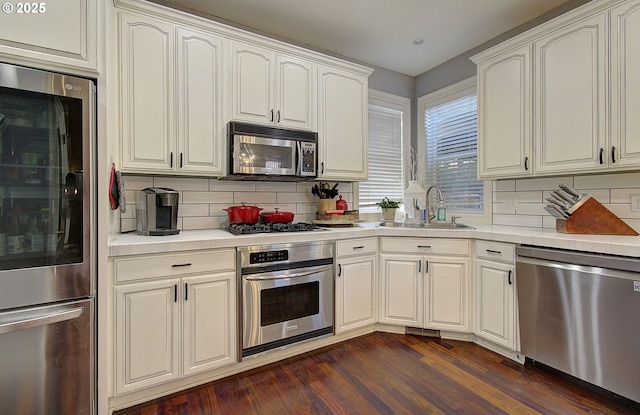 kitchen featuring light countertops, stainless steel appliances, dark wood-style floors, and a sink