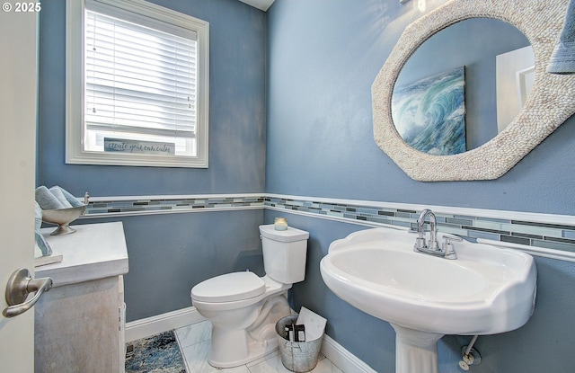 half bath featuring toilet, baseboards, and a sink