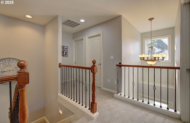 corridor featuring carpet flooring, an upstairs landing, a notable chandelier, visible vents, and baseboards