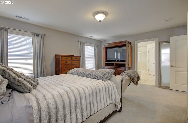 bedroom with light carpet, ensuite bath, and visible vents