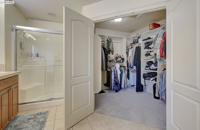 bathroom featuring vanity, a shower with shower door, and tile patterned floors