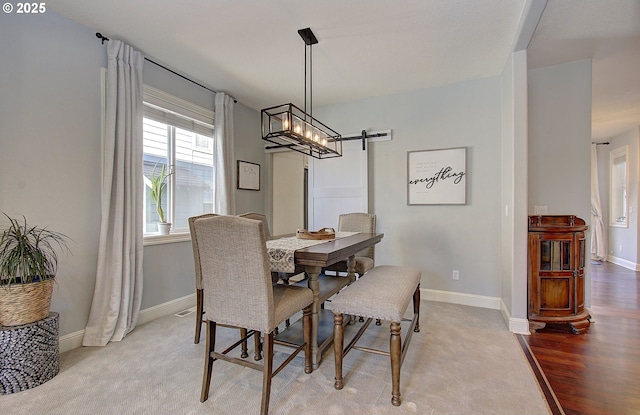 dining room with a barn door, wood finished floors, and baseboards