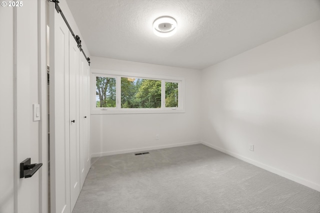 2390 Southshore Blvd, Lake Oswego, OR 97034 - unfurnished bedroom with a barn door, a textured ceiling, light colored carpet, and a closet