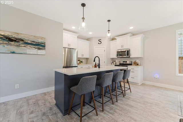 209 W Barbaras Way, Newberg, OR 97132 - kitchen with appliances with stainless steel finishes, light wood finished floors, white cabinets, a breakfast bar, and light countertops