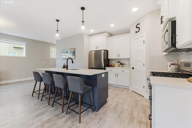 209 W Barbaras Way, Newberg, OR 97132 - kitchen featuring appliances with stainless steel finishes, light wood-type flooring, a breakfast bar area, backsplash, and an island with sink