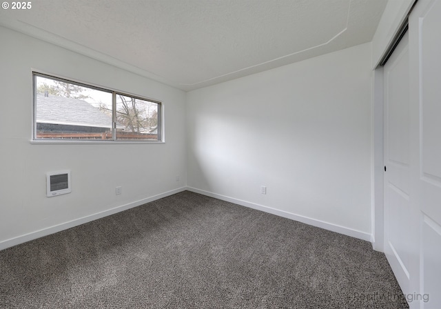 unfurnished bedroom with a textured ceiling, a closet, and dark colored carpet