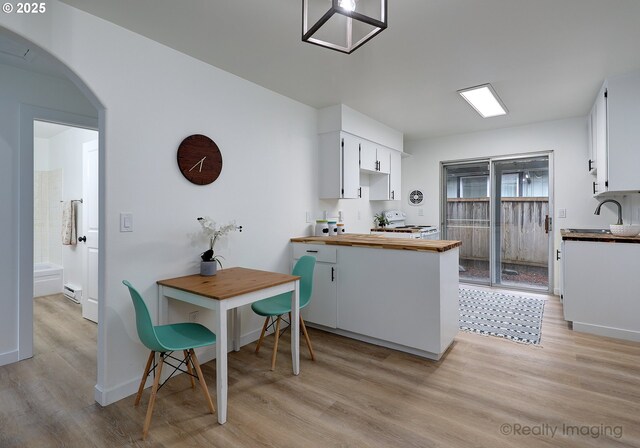 kitchen featuring wooden counters, white cabinets, a baseboard radiator, and light hardwood / wood-style flooring