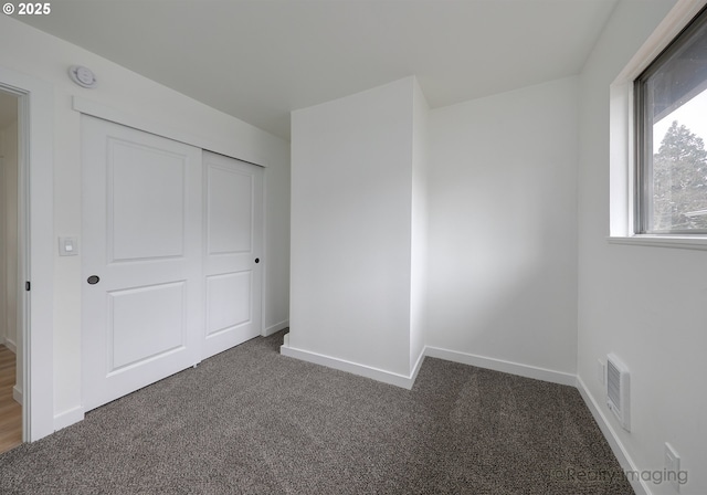 unfurnished bedroom featuring dark carpet and a closet