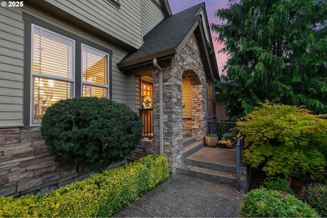 15475 SW Brighton Way, Beaverton, OR 97007 - exterior entry at dusk featuring stone siding and a shingled roof