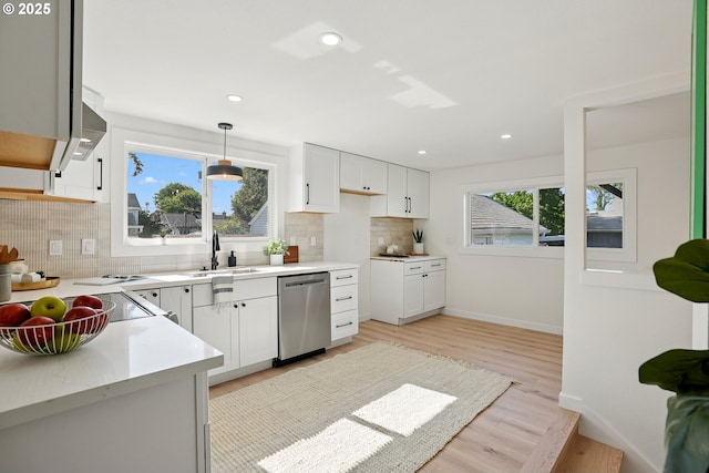 2615 N Gammans Pl, Portland, OR 97217 - kitchen with stainless steel dishwasher, backsplash, light countertops, light wood-style floors, and white cabinets