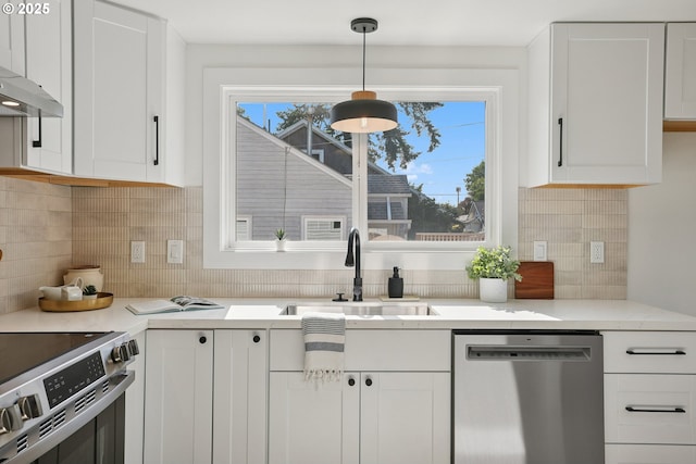 2615 N Gammans Pl, Portland, OR 97217 - kitchen with stainless steel appliances, white cabinetry, light countertops, tasteful backsplash, and hanging light fixtures