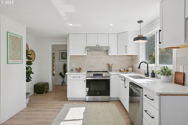2615 N Gammans Pl, Portland, OR 97217 - kitchen with appliances with stainless steel finishes, under cabinet range hood, decorative backsplash, white cabinets, and light countertops