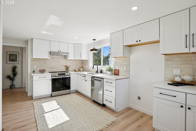2615 N Gammans Pl, Portland, OR 97217 - kitchen with stainless steel appliances, under cabinet range hood, decorative backsplash, light wood finished floors, and white cabinets