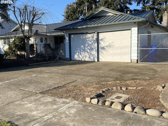 exterior space featuring concrete driveway, a standing seam roof, metal roof, fence, and a garage