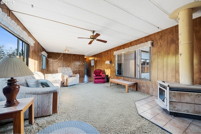 carpeted living room featuring decorative columns, wooden walls, and ceiling fan