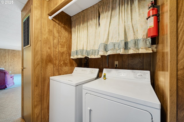 washroom with separate washer and dryer, carpet, and wooden walls