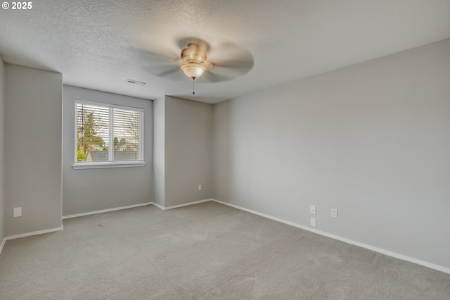 empty room with visible vents, baseboards, light carpet, a textured ceiling, and a ceiling fan