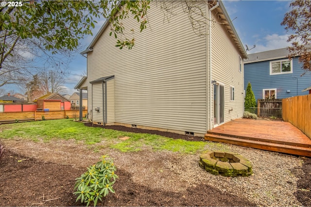 rear view of house featuring fence, a yard, a fire pit, a wooden deck, and crawl space