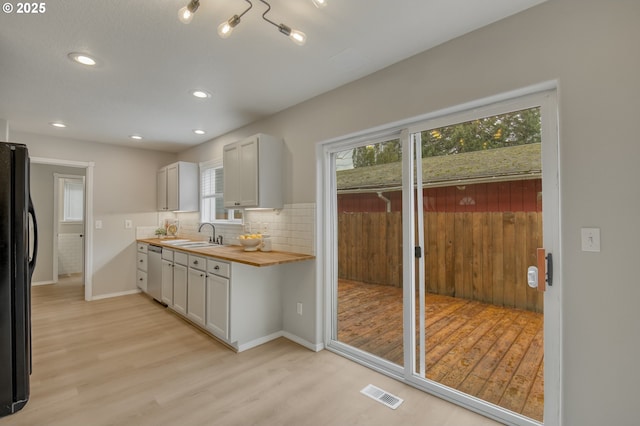 kitchen featuring visible vents, wooden counters, freestanding refrigerator, stainless steel dishwasher, and light wood-type flooring