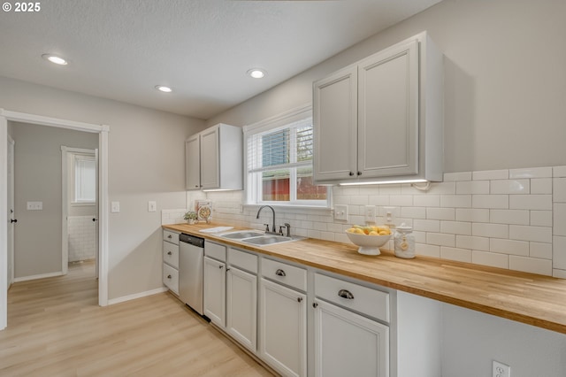 kitchen with a sink, wood counters, and stainless steel dishwasher