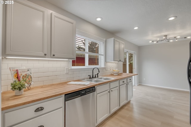 kitchen featuring backsplash, dishwasher, butcher block counters, and a sink