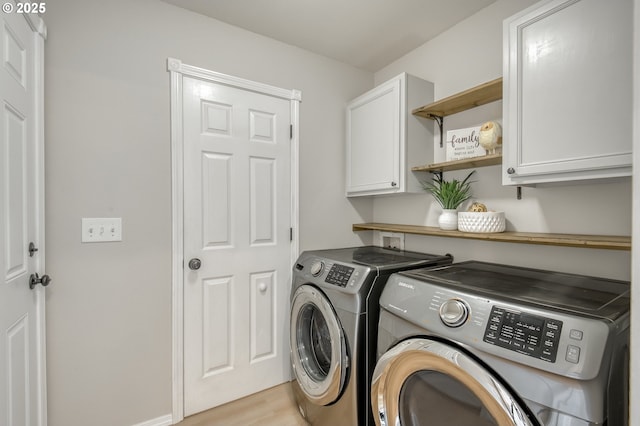 laundry area featuring washer and clothes dryer, cabinet space, and light wood finished floors