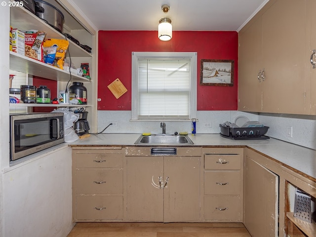 kitchen featuring stainless steel microwave, light countertops, open shelves, and a sink