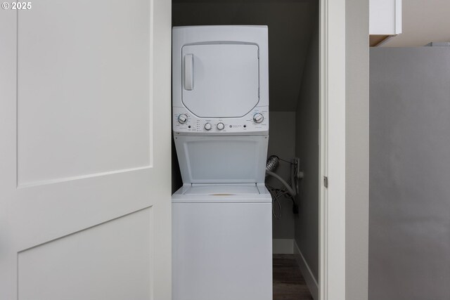 washroom featuring stacked washer / drying machine and dark wood-type flooring